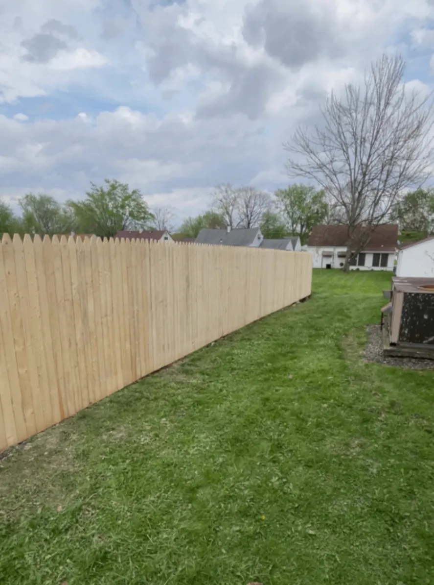 New pale cedar privacy fence running along a green lawn
